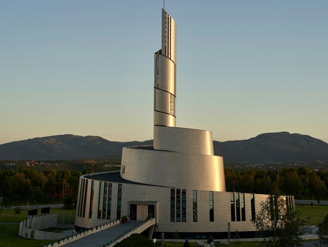 Modern spiral church tower at sunset with mountains in the background