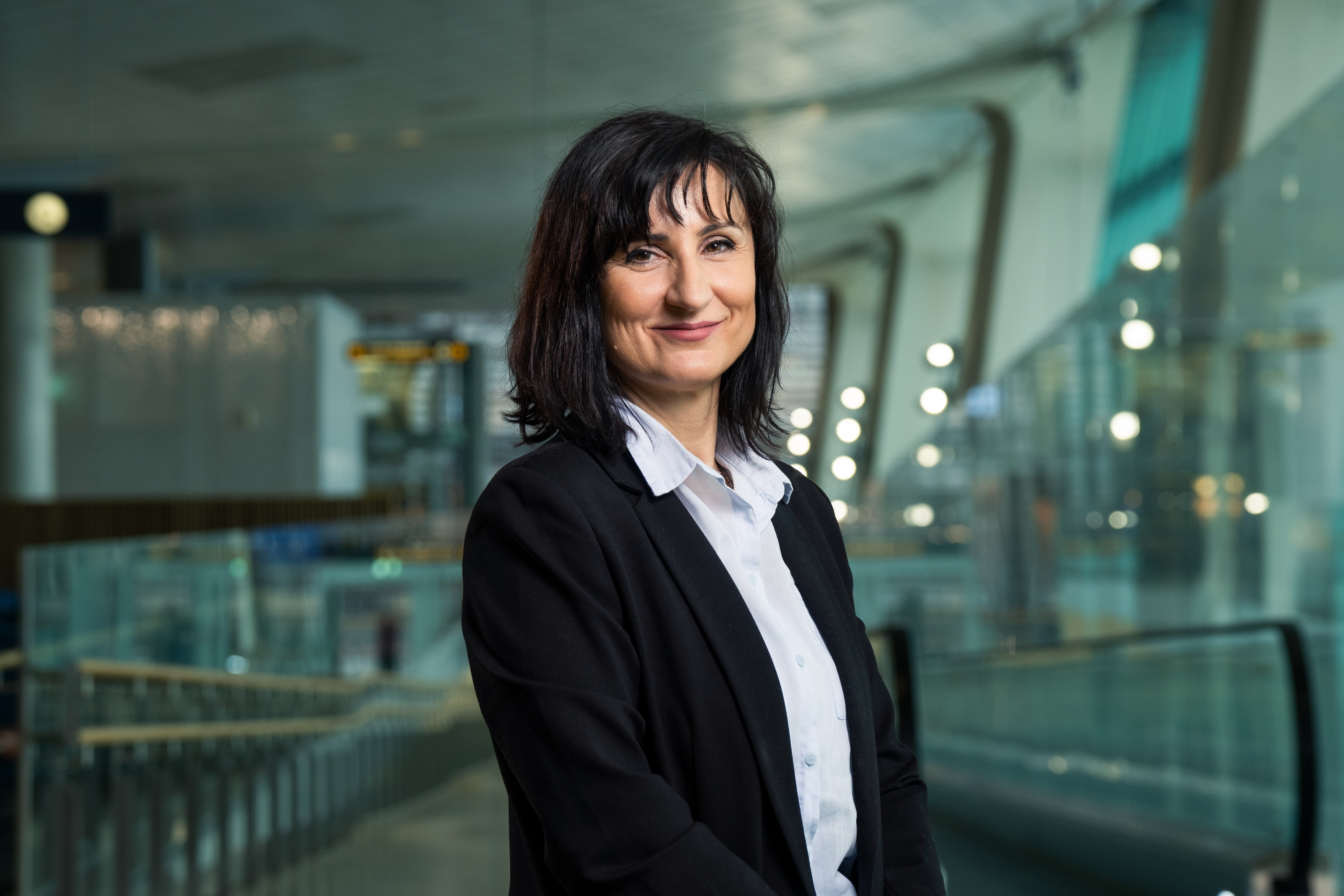 Profesjonell kvinne i forretningsklær som smiler i en moderne kontorbygning