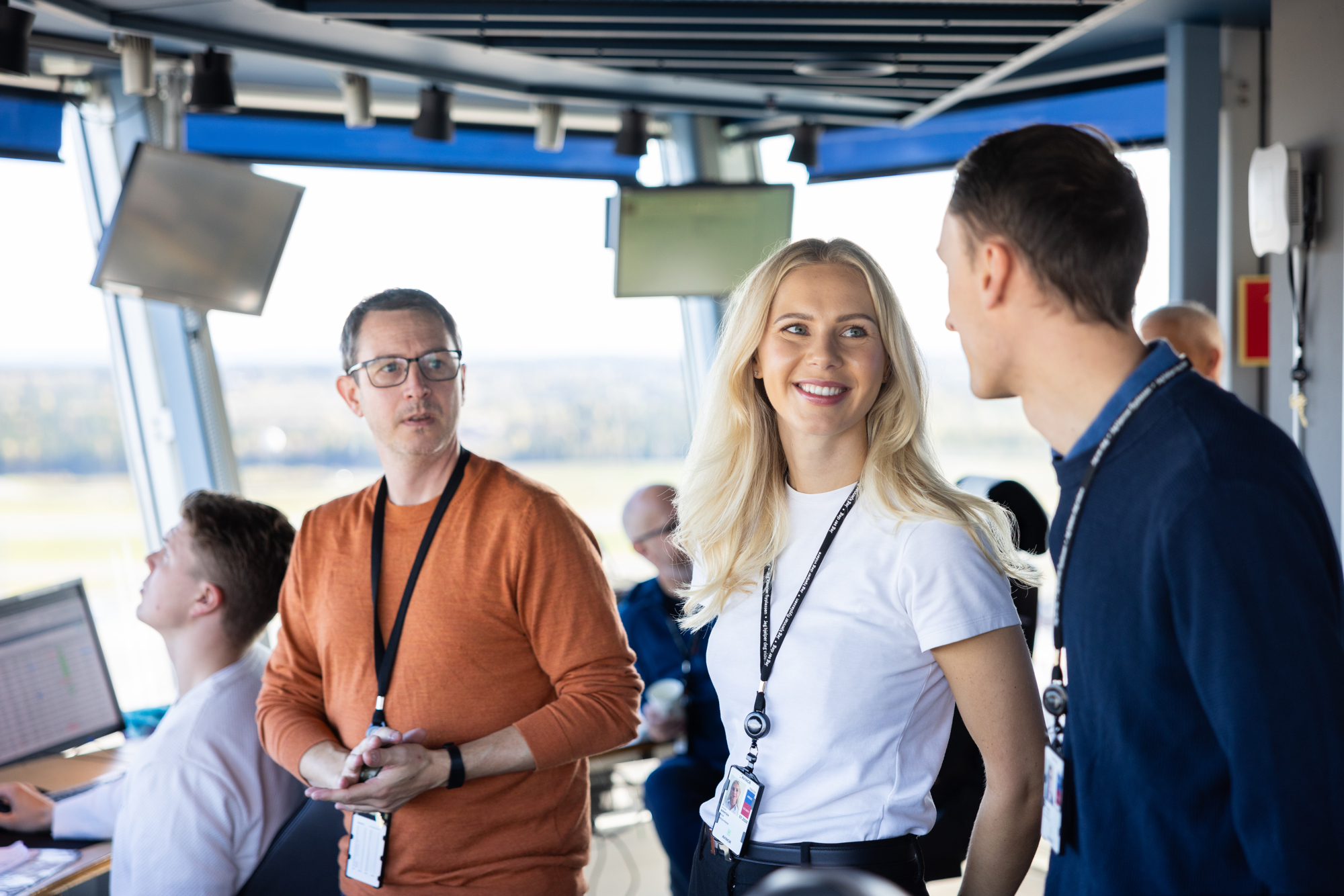 Lufttrafikktjenesteteam i arbeid i et moderne tårn, diskuterer flyoperasjoner og overvåker skjermer