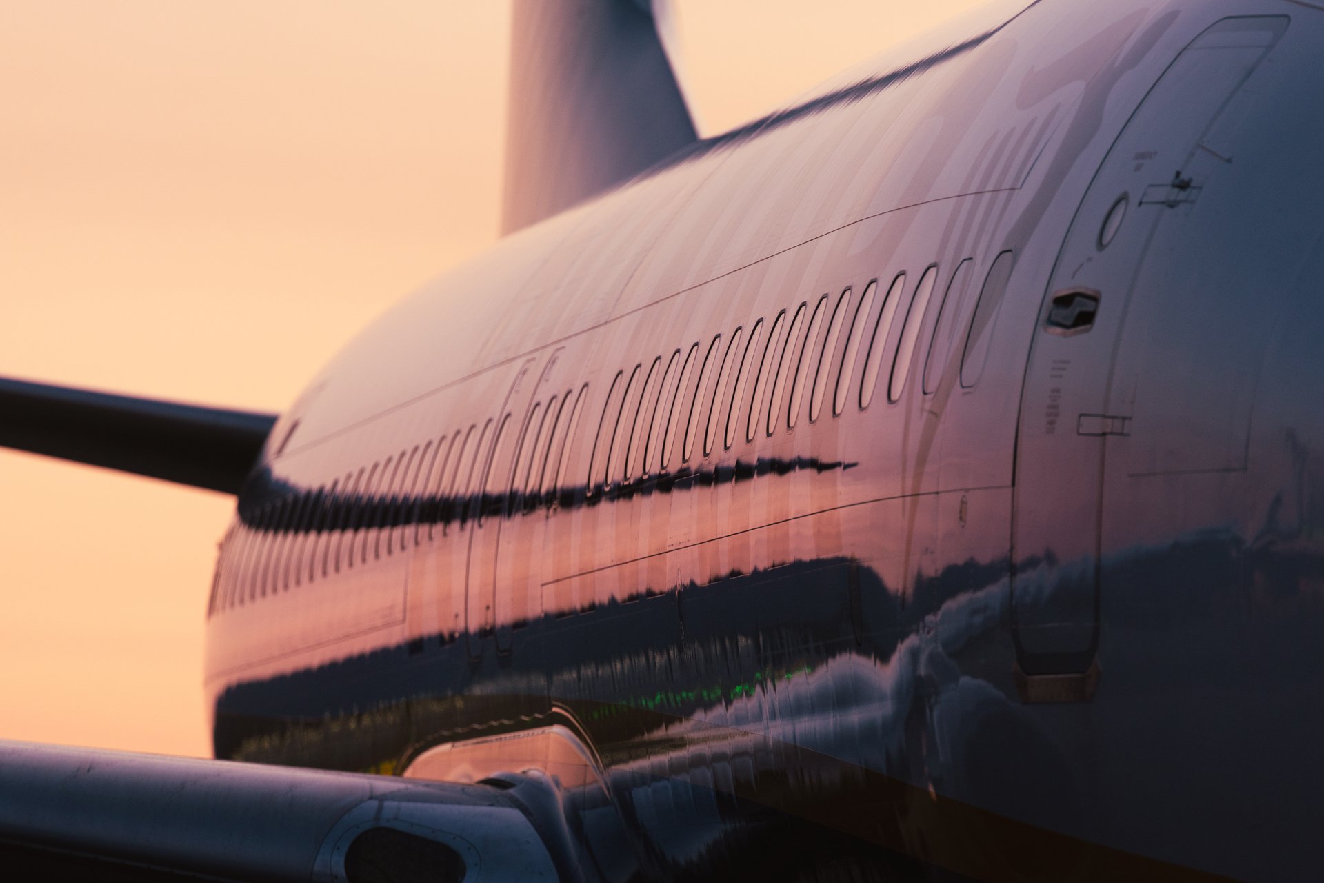 Sidebilde av et fly som reflekterer de varme fargene fra en solnedgang, og fremhever reise og luftfart