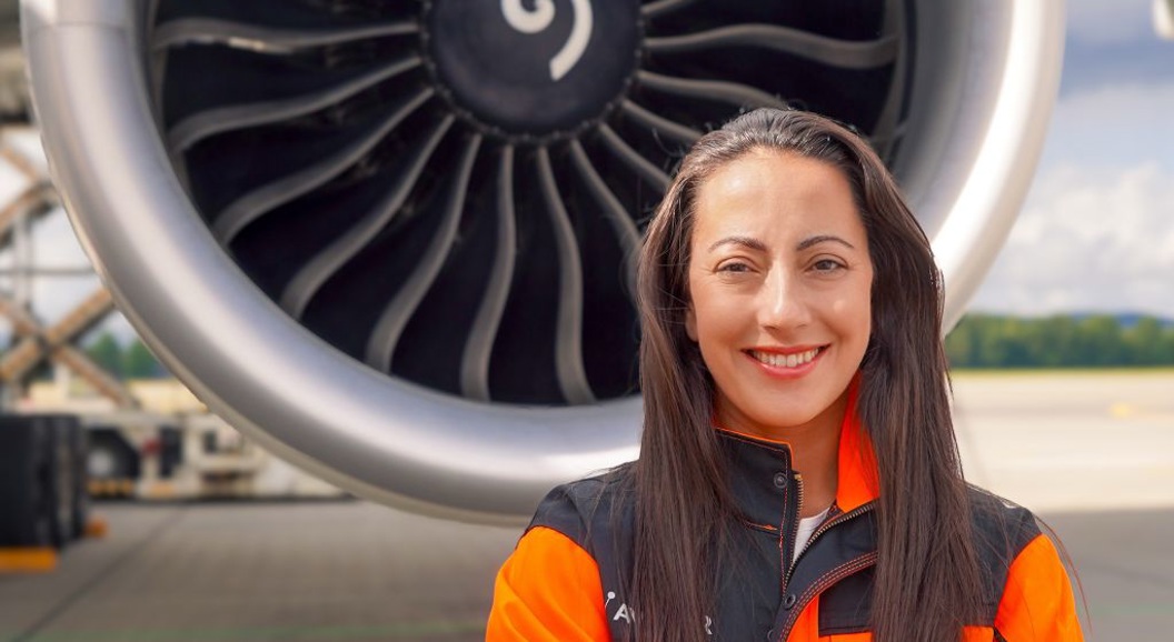 Eva Beate Lande i oransje synlighetstøy foran en stor turbofan-motor.