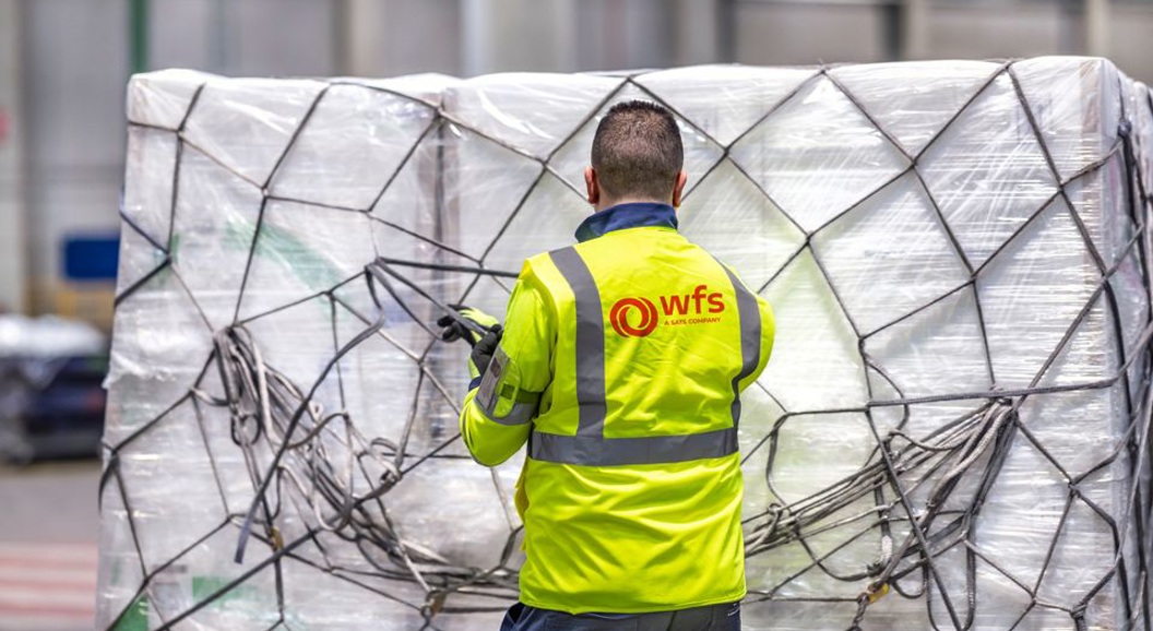 WFS-ansatt i gul refleksjakke sikrer en stor palletert last.