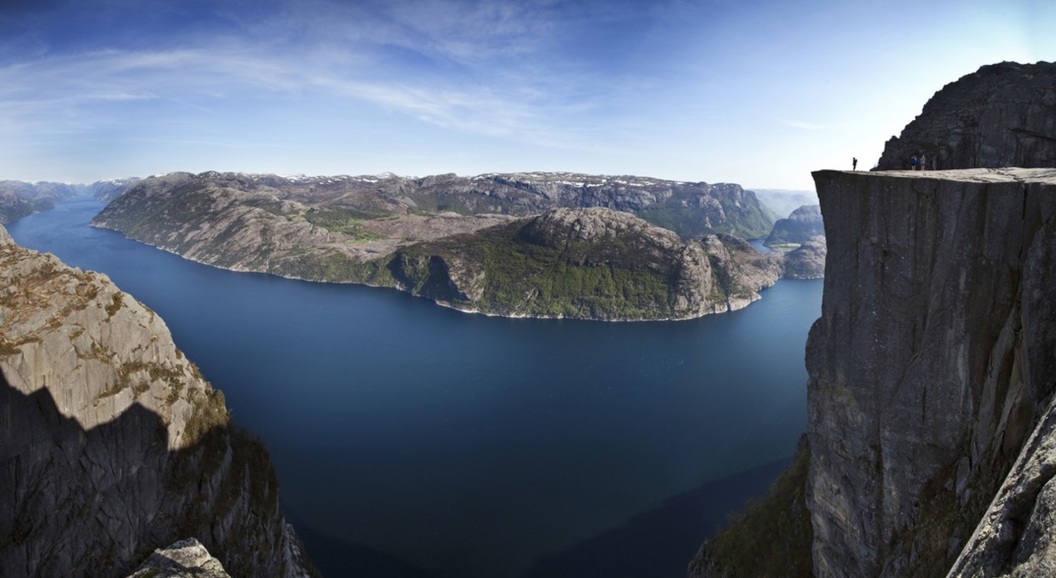 Utsikt fra klippekanten av Preikestolen over Lysefjorden i Norge, med blå himmel og steinete landskap