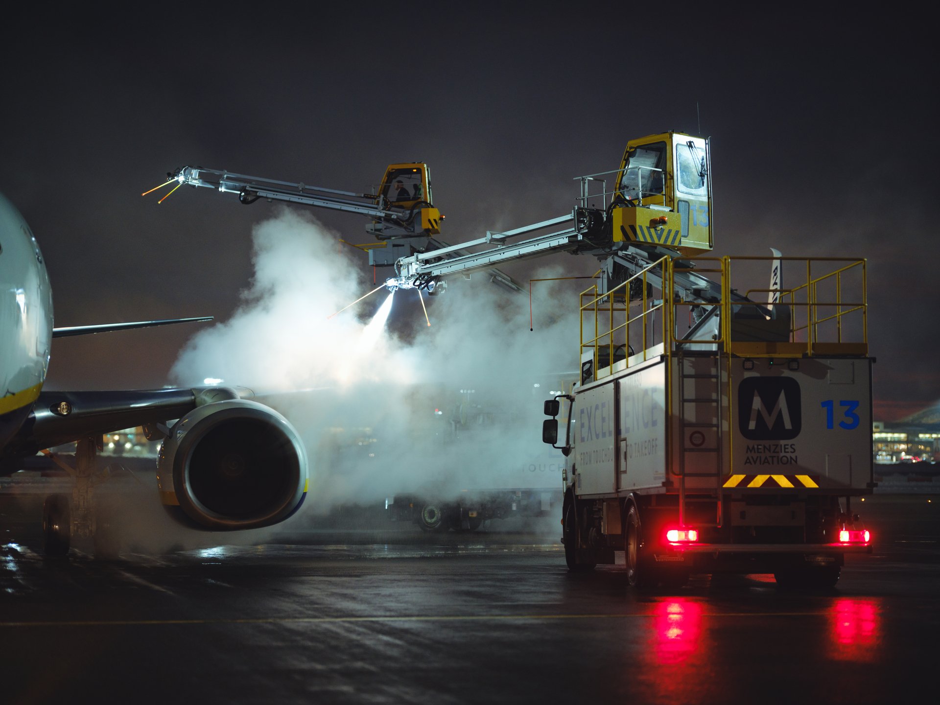 Fly som avises om natten på en flyplass tarmac, ved bruk av spesialiserte kjøretøy og utstyr for å sikre trygge flyoperasjoner