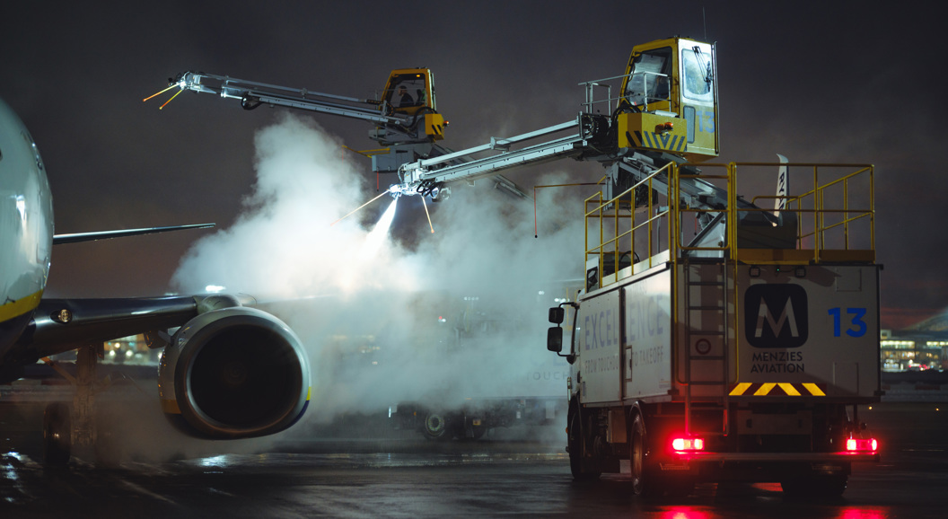 Fly som avises om natten på en flyplass tarmac, ved bruk av spesialiserte kjøretøy og utstyr for å sikre trygge flyoperasjoner