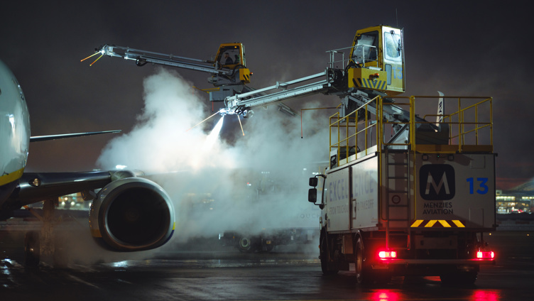 Fly som avises om natten på en flyplass tarmac, ved bruk av spesialiserte kjøretøy og utstyr for å sikre trygge flyoperasjoner